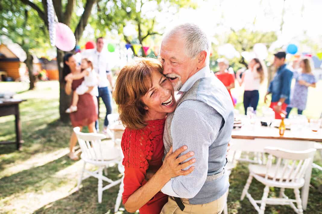 A senior couple dancing on a garden party outside in the backyard. Eine rechtzeitige Lebensplanung ermöglicht später „glücklich sein“