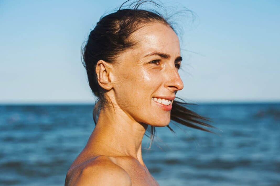 Smiling young woman at the sea looks to the side Vitamin-D-Booster Sonne
