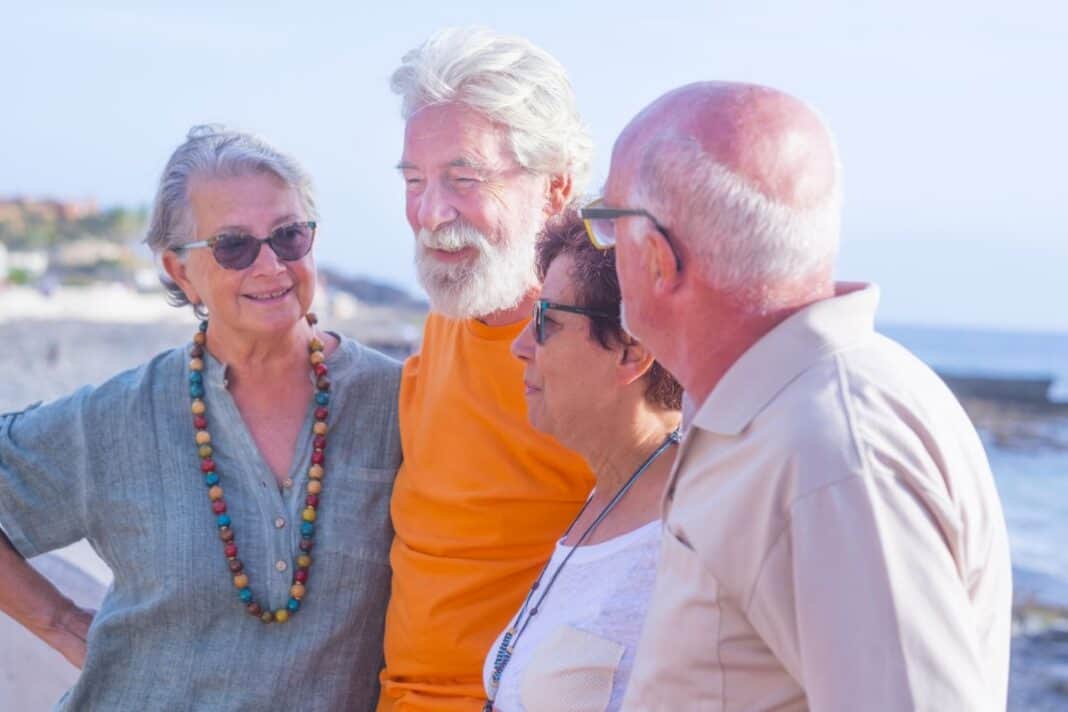 group of four happy seniors and mature people talking and having Urlaub trotz Demenz: Das sollten Pflegepersonen wissen