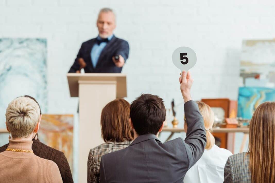 back view of buyer showing auction paddle with number five to auctioneer during auction Fundsachenversteigerung im Rathaus