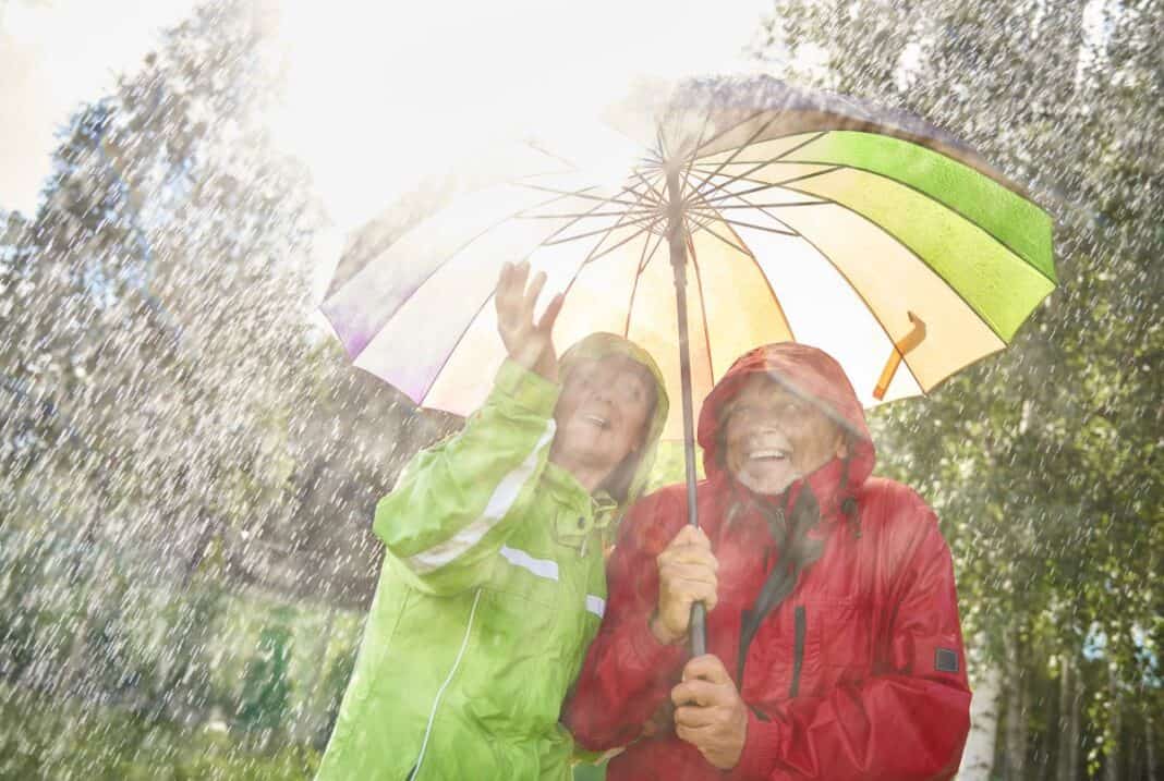 Happy couple standing with umbrella Hitzewelle oder Dauerregen: Echt nordische Tipps für Extremwetter