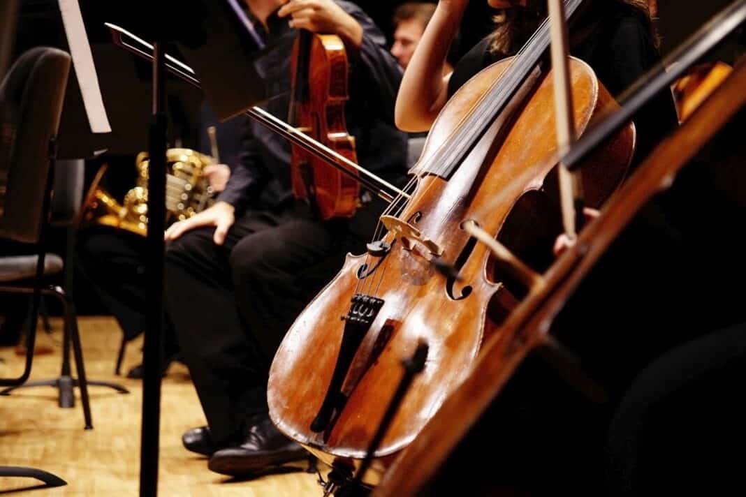 Musician rests his cello on stage surrounded by the rest of the Kammerphilharmonie Köln – Kammerkonzert
