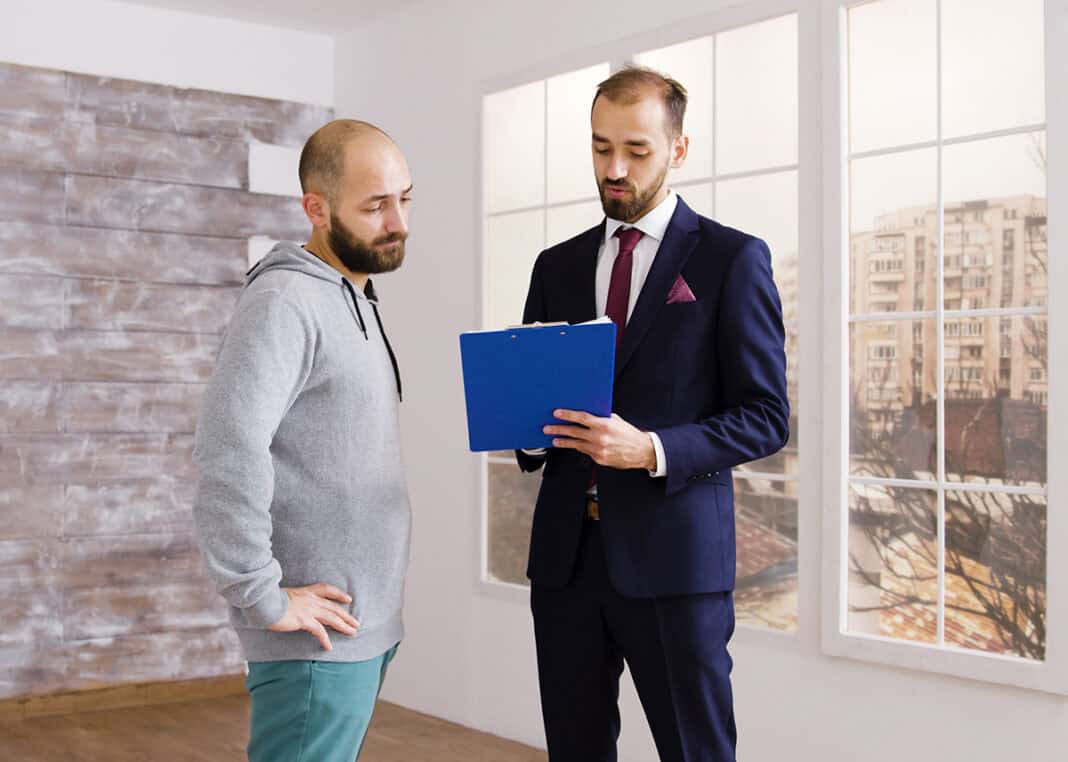 Real estate agent in business suit describes apartment to client Gekauft wie gesehen? Wann der Verkäufer einer gebrauchten Immobilie trotz Gewährleistungsausschluss haftet