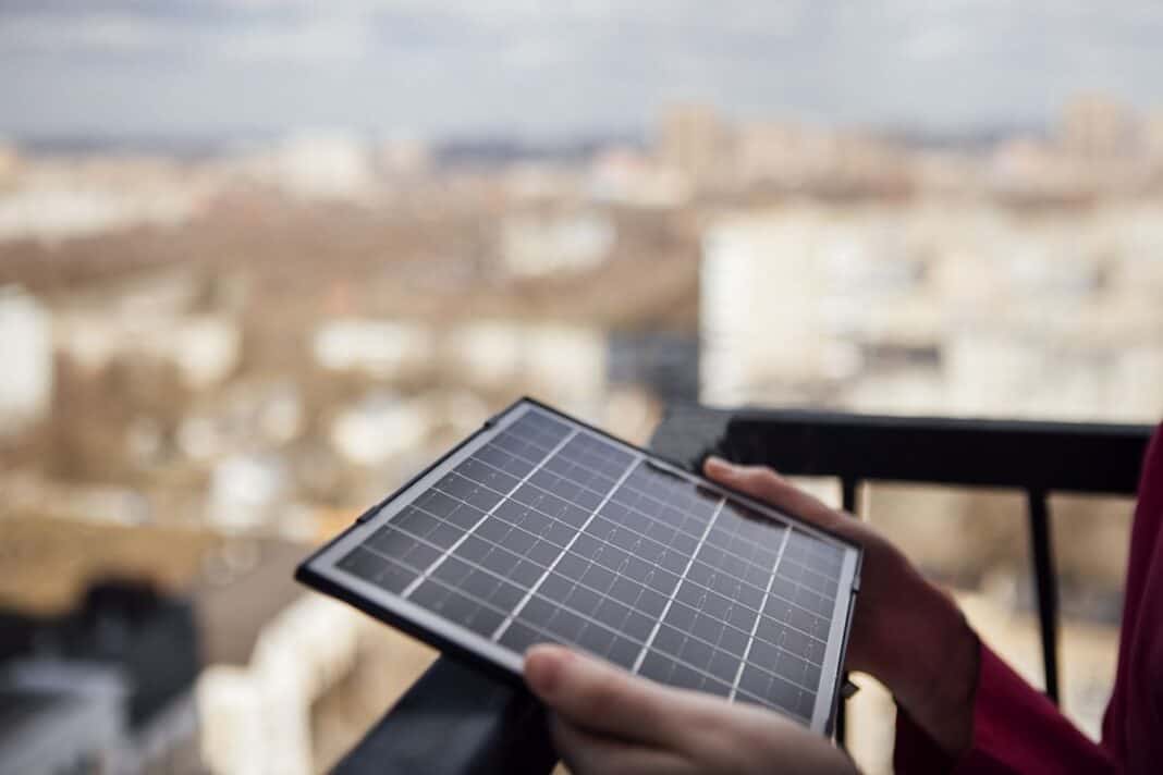 Individual holding a small solar panel on a balcony with a blurr Welche Heim-Speicher lohnen sich bei 600–800 Wp?